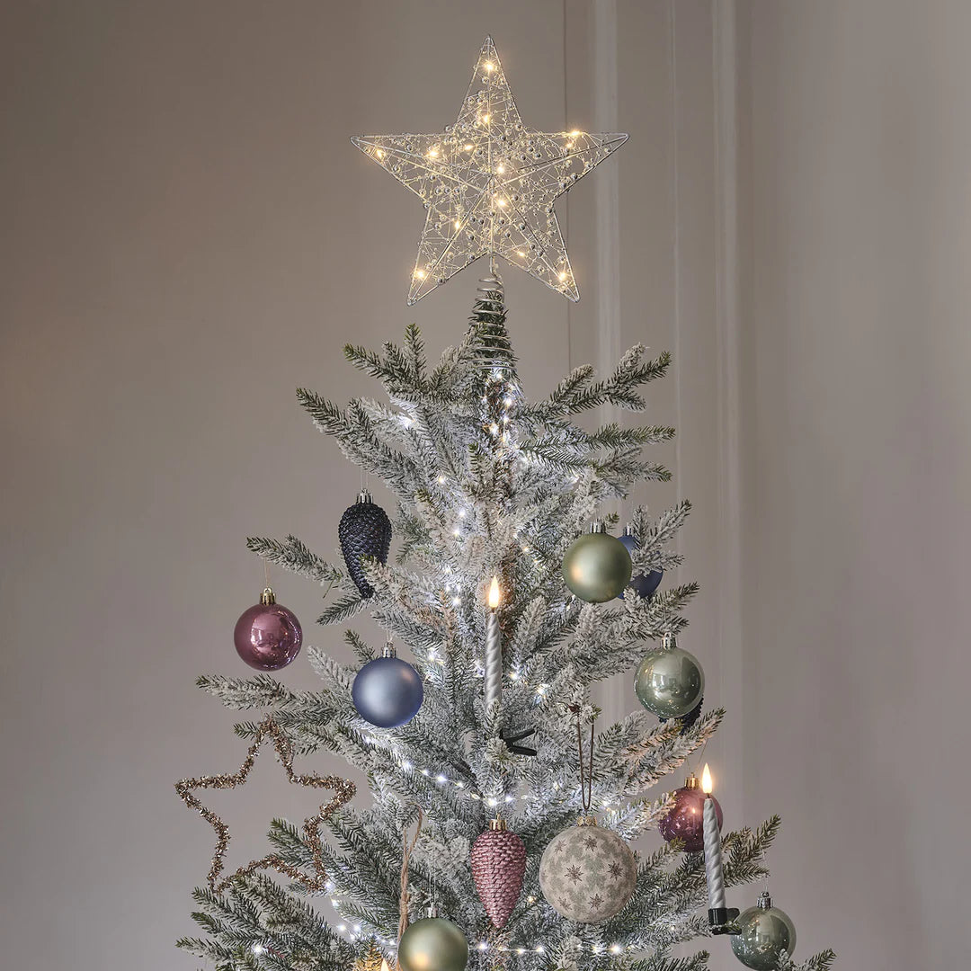 Weihnachtsbaumspitze mit beleuchtetem Stern und silbernen LED-Kerzen, geschmückt mit Kugeln und Lichterketten