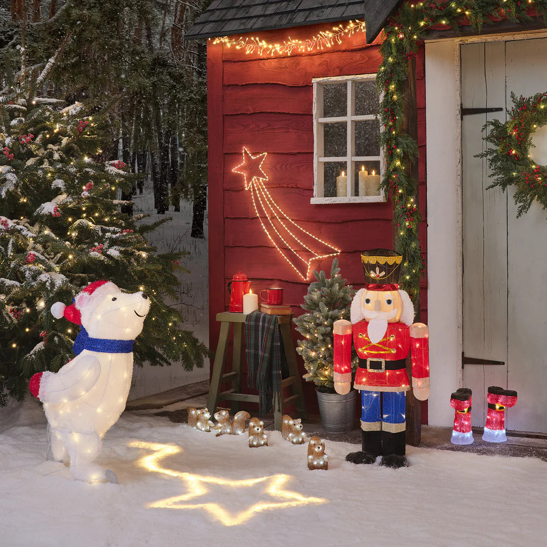 Weihnachtsdekoration mit beleuchtetem Nussknacker, Eisbär und roten LED-Stiefeln vor rotem Haus