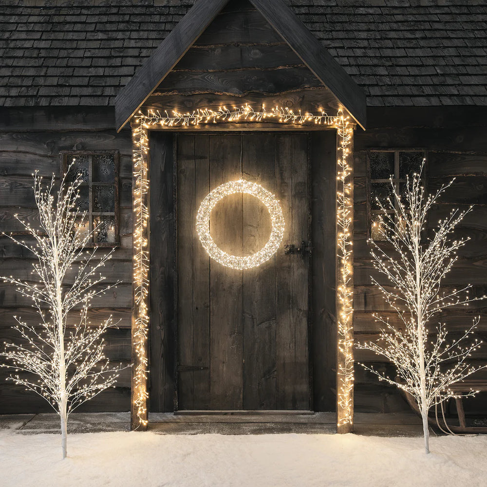 Weihnachtlich beleuchteter Eingang mit LED-Kranz an Holztür und Lichterketten am Rahmen