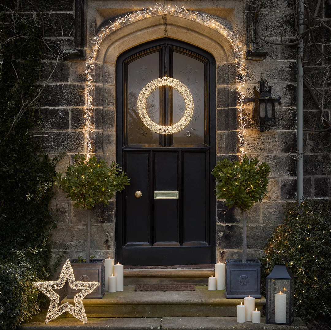 Schwarze Haustür mit silbernem LED-Weihnachtskranz, Stern und Kerzen auf Treppe