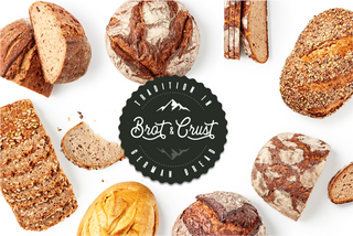 Assorted bread loaves with 'Brat & Crust' logo in the center on a white background