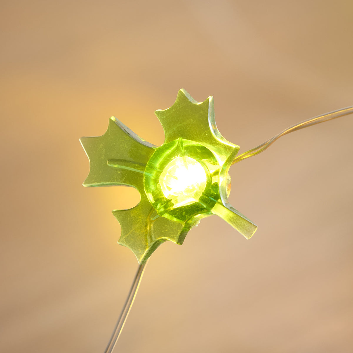 Leuchtendes grünes Ahornblatt aus Kunststoff an der herbstlichen Lichterkette