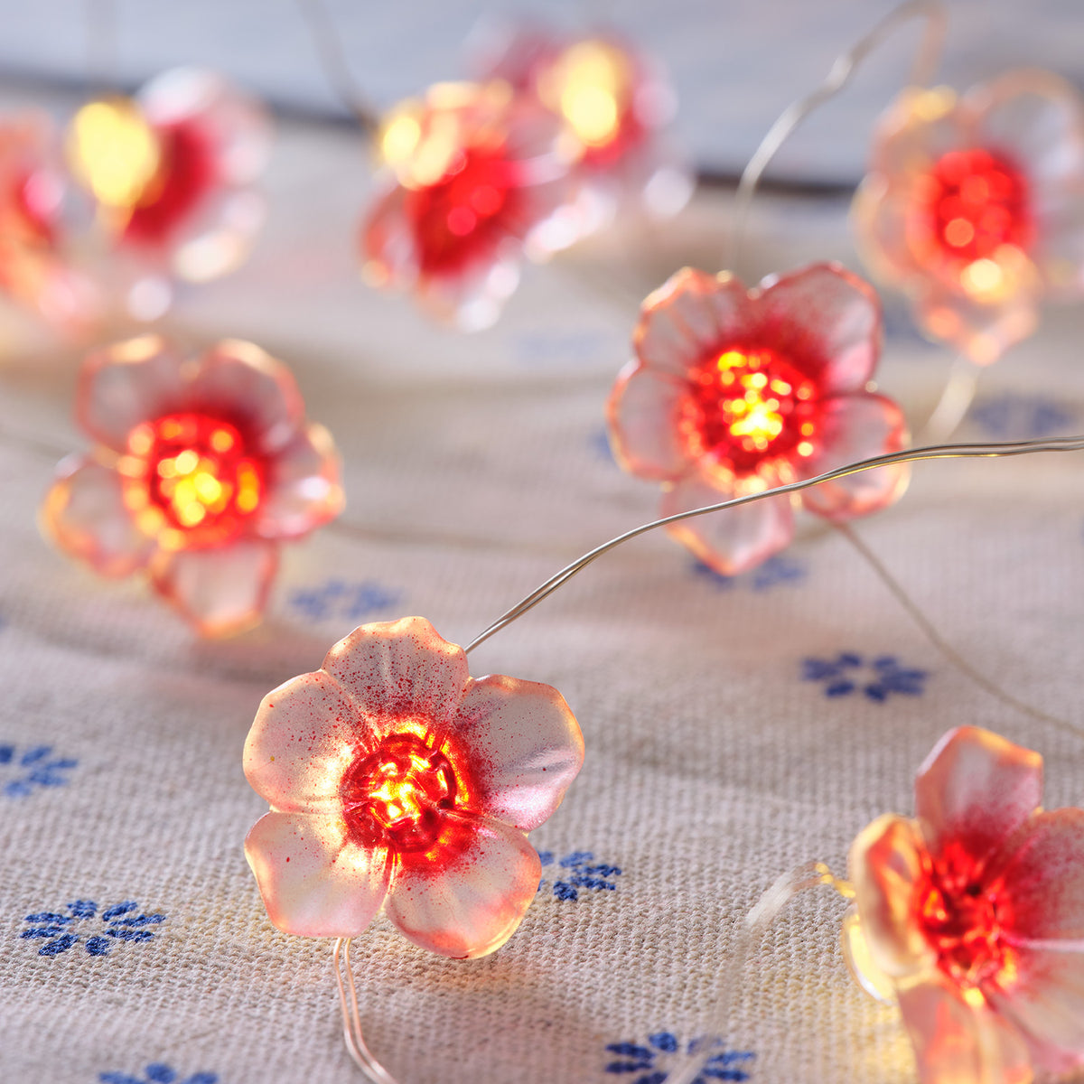 Nahaufnahme der pinken Kirschblüten mit warmweißen LEDs auf hellem Stoff