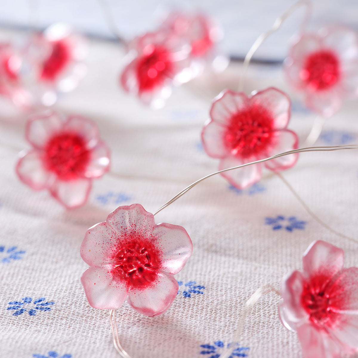 Detailaufnahme der leuchtenden Kirschblüten auf Lichterkette auf hellem Untergrund