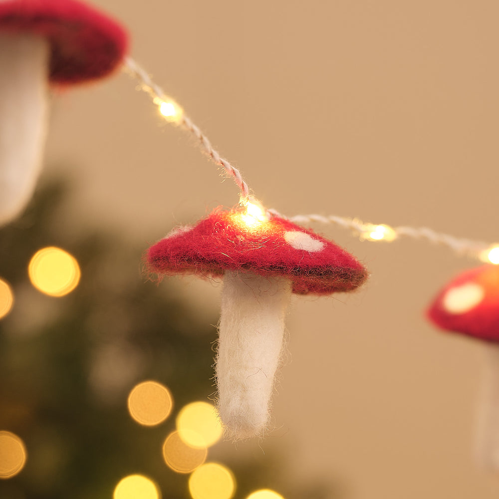 Nahaufnahme eines beleuchteten Filz-Fliegenpilzes an einer Lichterkette, roter Hut mit weißen Punkten und weißem Stiel.