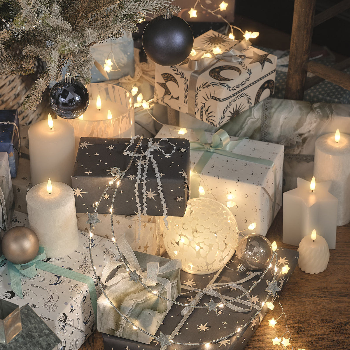Weiße Stern-LED-Lichterkette in festlicher Weihnachtsdekoration mit Geschenkboxen, Kerzen und Weihnachtskugeln, warmweiße Lichter in elegant gestalteter Wohn-Inszenierung.