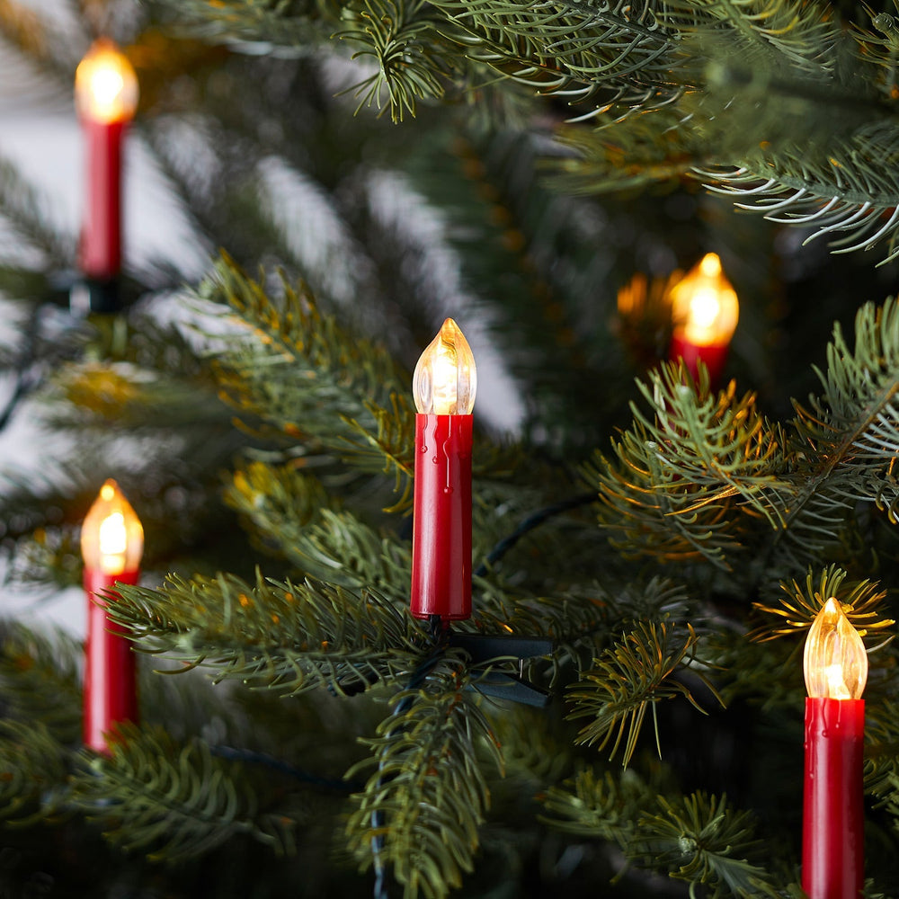 Rote Weihnachtsbaumkerzen mit warmweißen LEDs an grünen Tannenzweigen