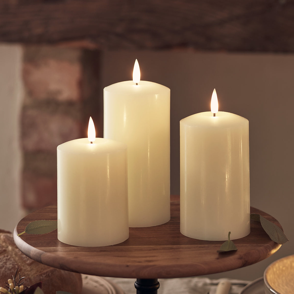 Drei beleuchtete LED-Kerzen auf einem Holztablett vor dunklem Hintergrund