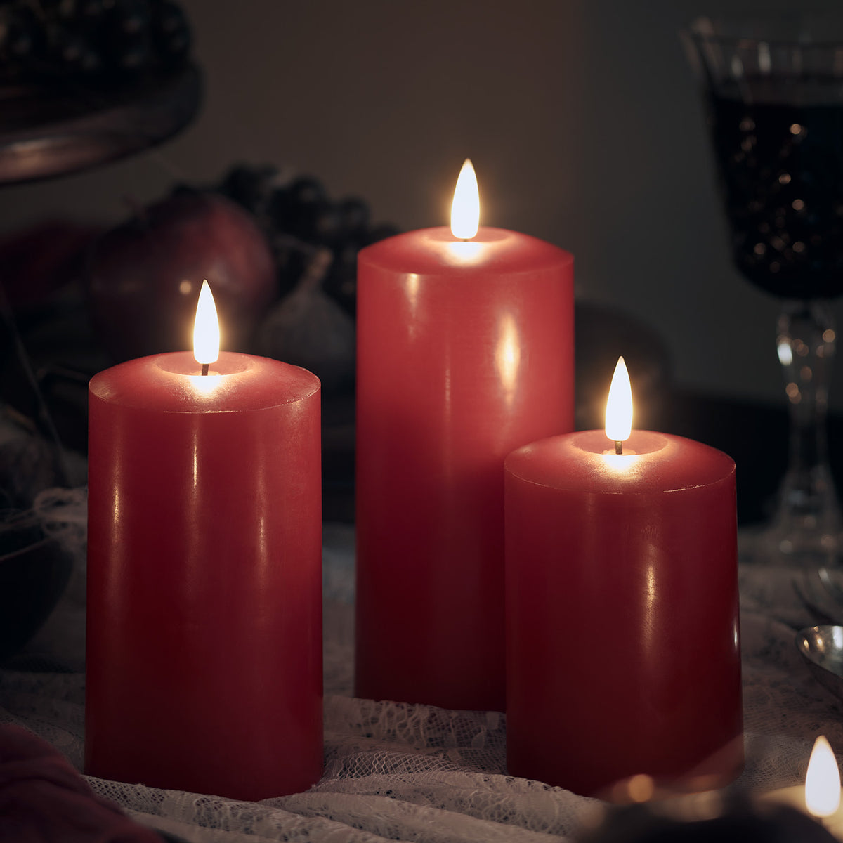 Drei rote LED-Kerzen aus Echtwachs mit flackernder Flamme in dunkler Umgebung