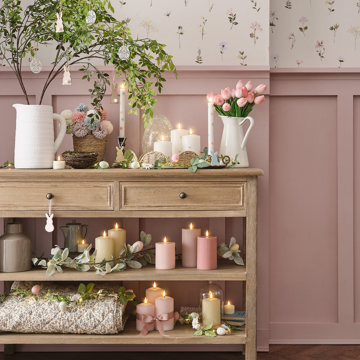 Frühlingsdeko mit rosa LED Kerzen, Tulpen, Osterzweigen und Büchern auf Holzkommode