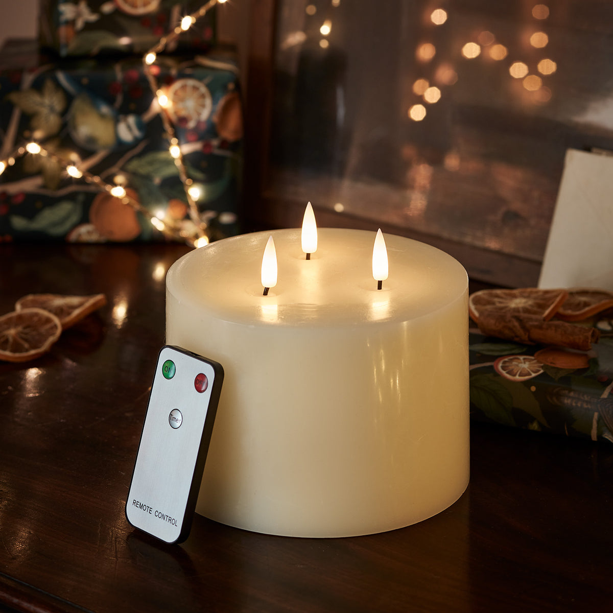 Dreidochtige LED-Kerze mit Fernbedienung vor weihnachtlicher Dekoration