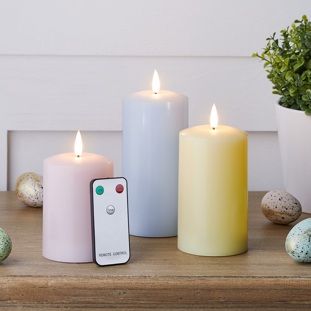 LED Stumpenkerzen in Pastellfarben mit Fernbedienung und Ostereiern auf Holztisch
