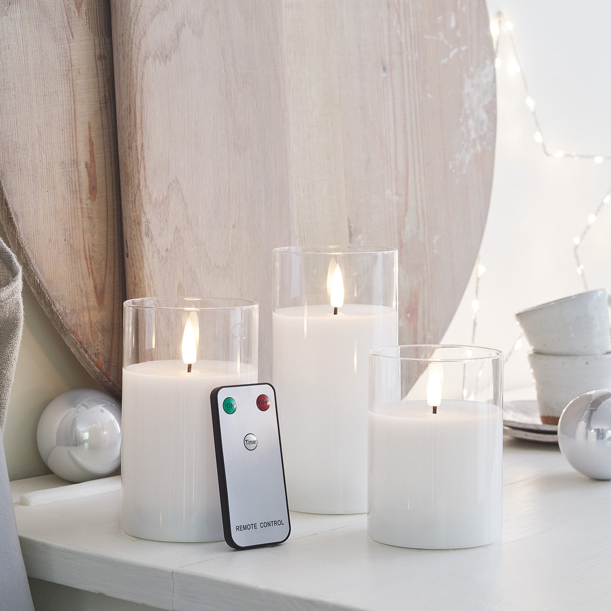 LED-Kerzen Trio mit Fernbedienung vor Holzbrett und Weihnachtsdeko