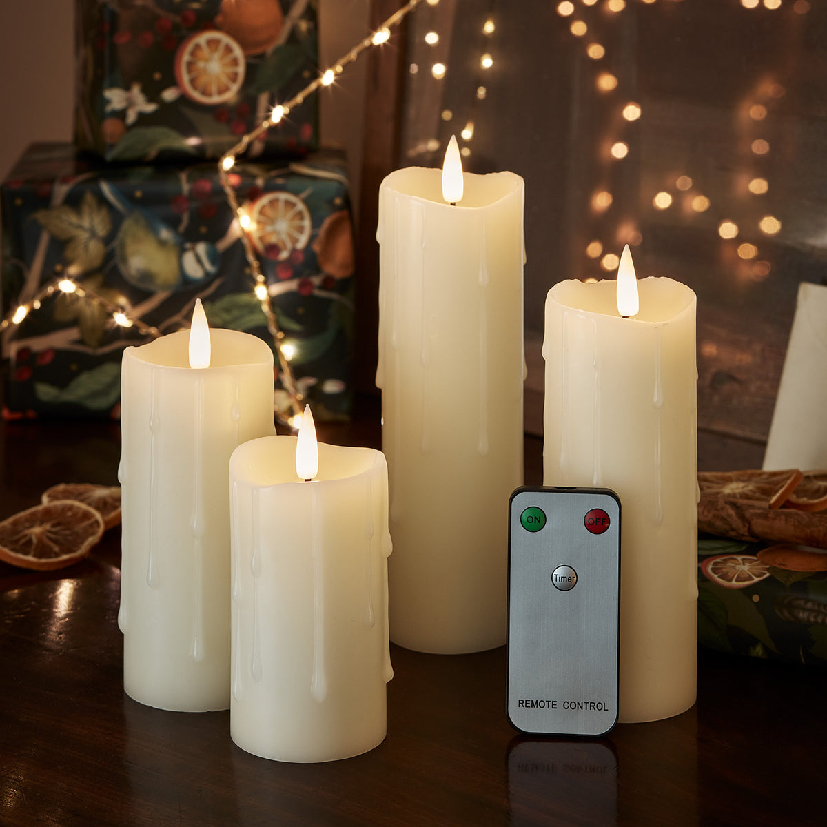 Vier brennende LED-Kerzen mit Wachstropfen und Fernbedienung auf dunklem Untergrund