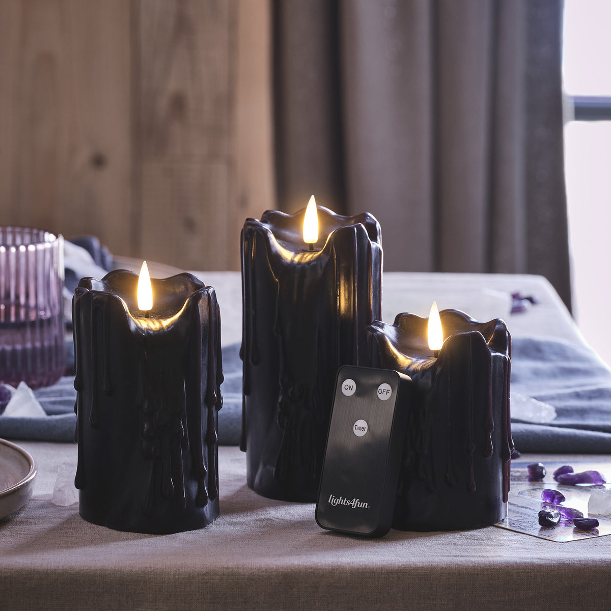Schwarze LED Stumpenkerzen mit Wachstropfen und Fernbedienung auf Tisch mit flackernder Flamme