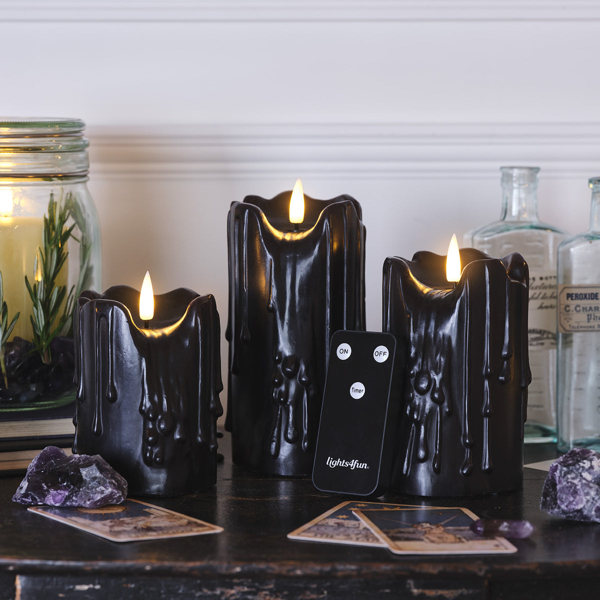 Schwarze LED Stumpenkerzen mit Wachstropfen, Tarotkarten und Fernbedienung auf dunklem Tisch