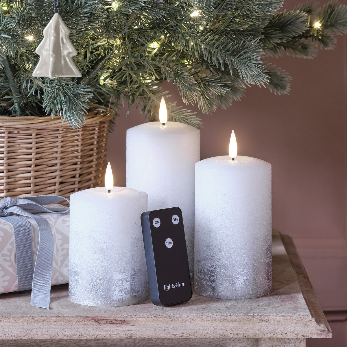 Drei silber ombré LED Kerzen mit Fernbedienung auf Holztisch vor Weihnachtsdeko
