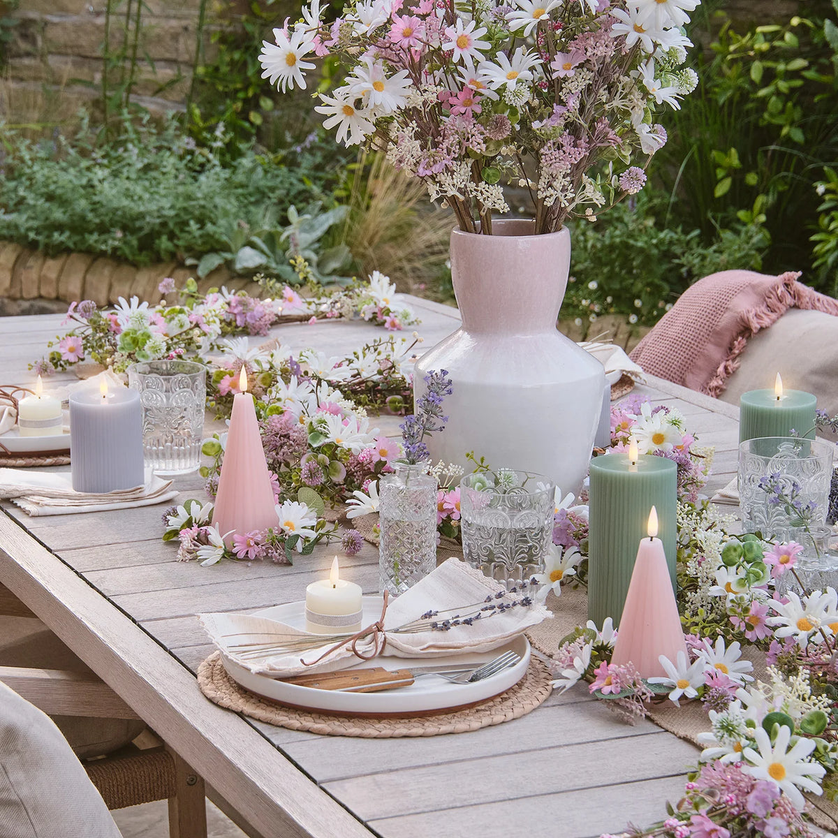 Outdoor-Tisch mit rosa LED-Kegelkerzen, Blumen und gedecktem Platz