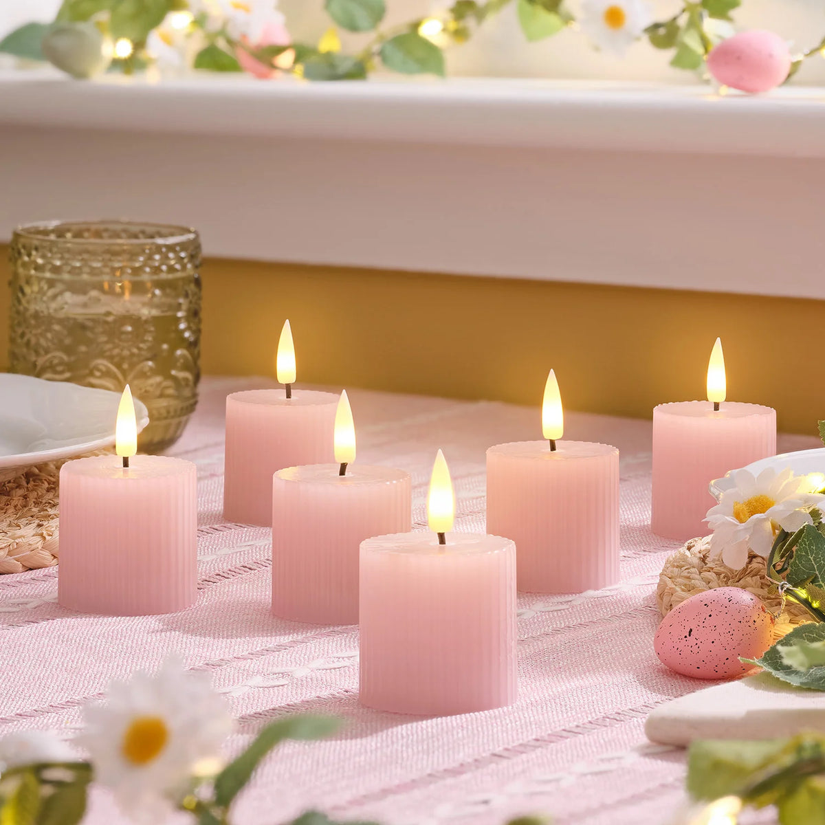Sechs rosa geriffelte LED-Votivkerzen mit warmweiß flackernden Flammen auf einem Tisch dekoriert