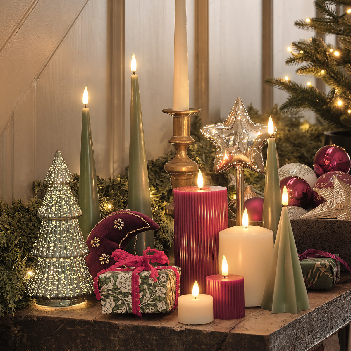 Weihnachtliche Dekoration mit LED-Sternleuchte, Kerzen und Tannengrün auf Kaminsims