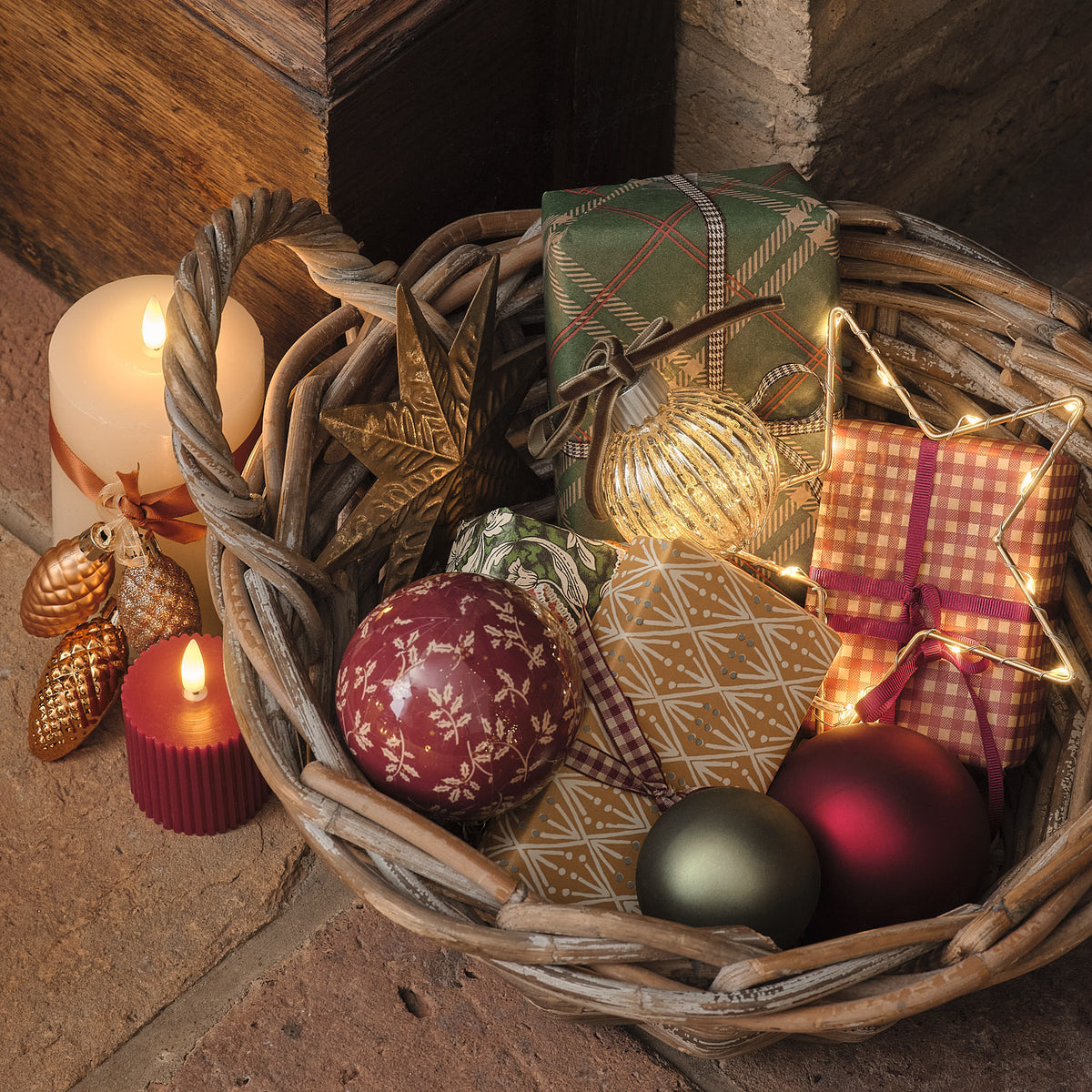 Weidenkorb mit Weihnachtsgeschenken, Kerzen und einer leuchtenden LED-Weihnachtskugel