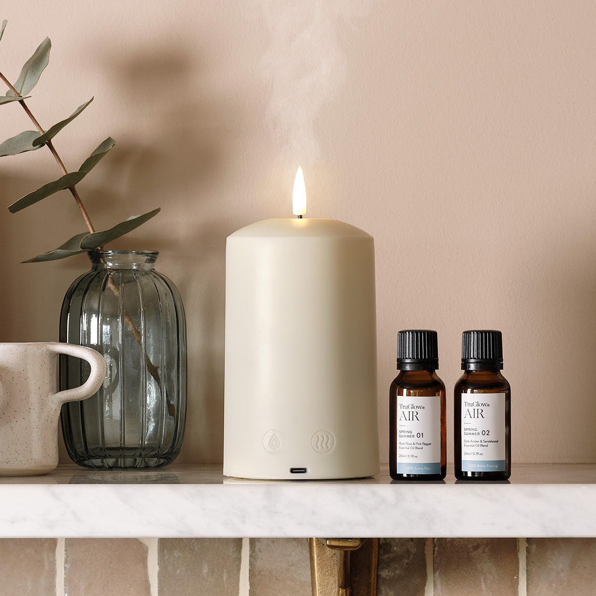 TruGlow AIR Duftdiffusor-Kerze mit zwei Duftölfläschchen auf Marmorablage