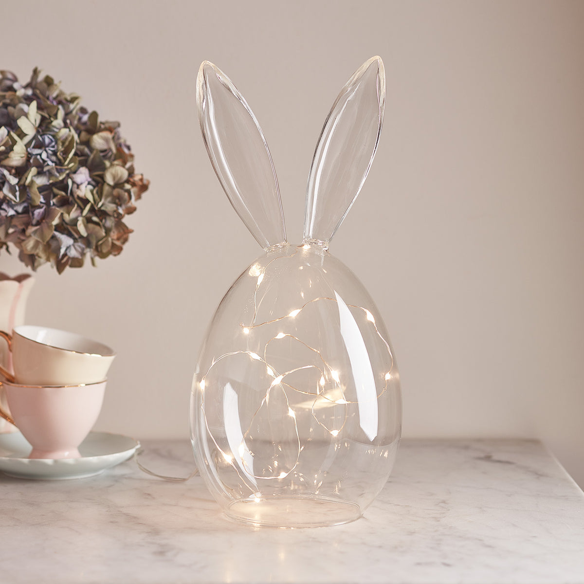 Glasglocke in Hasenform mit langen Ohren und Micro LED Lichterkette auf Marmorplatte