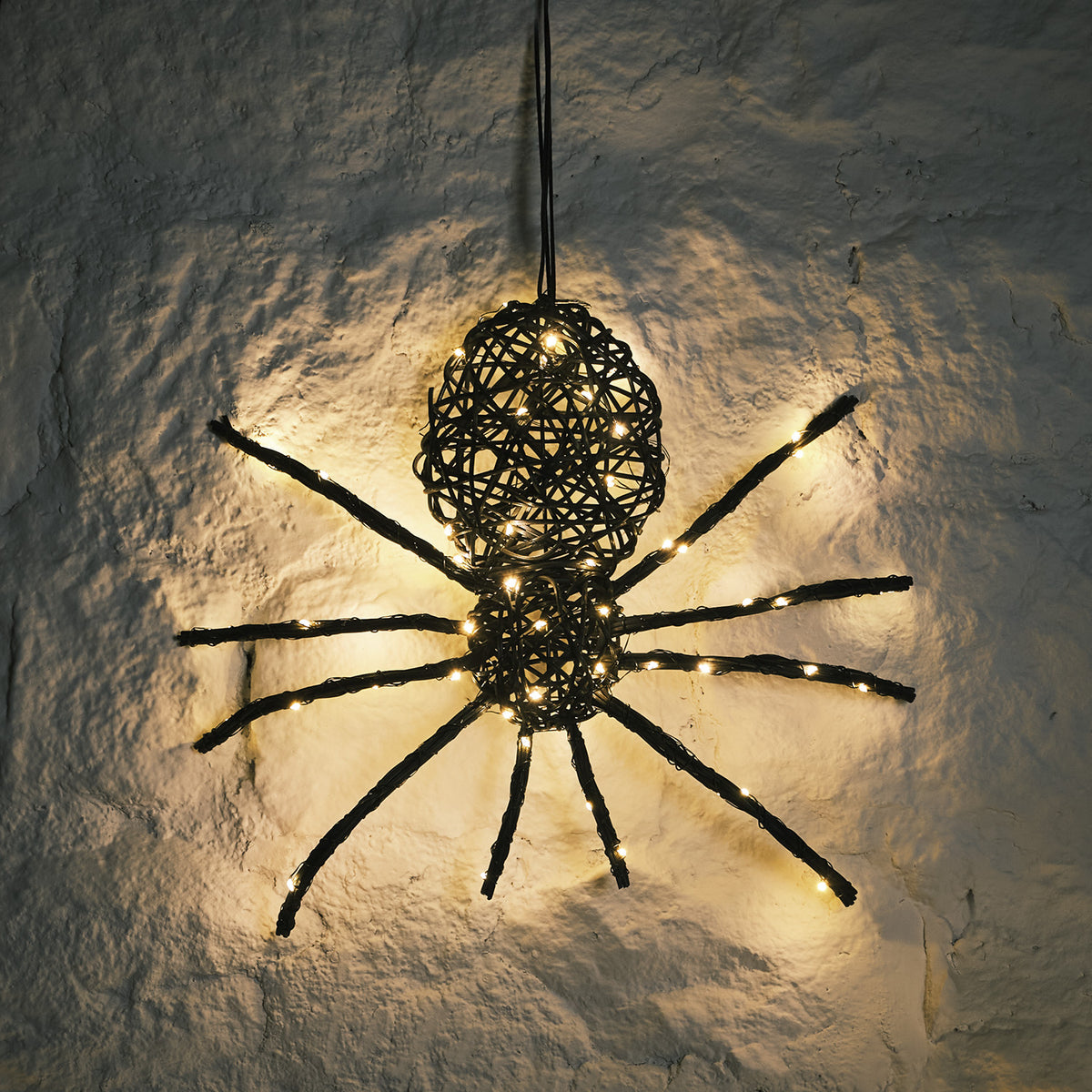 LED beleuchtete Rattan-Spinne mit warmweißen Lichtern an weißer Wand