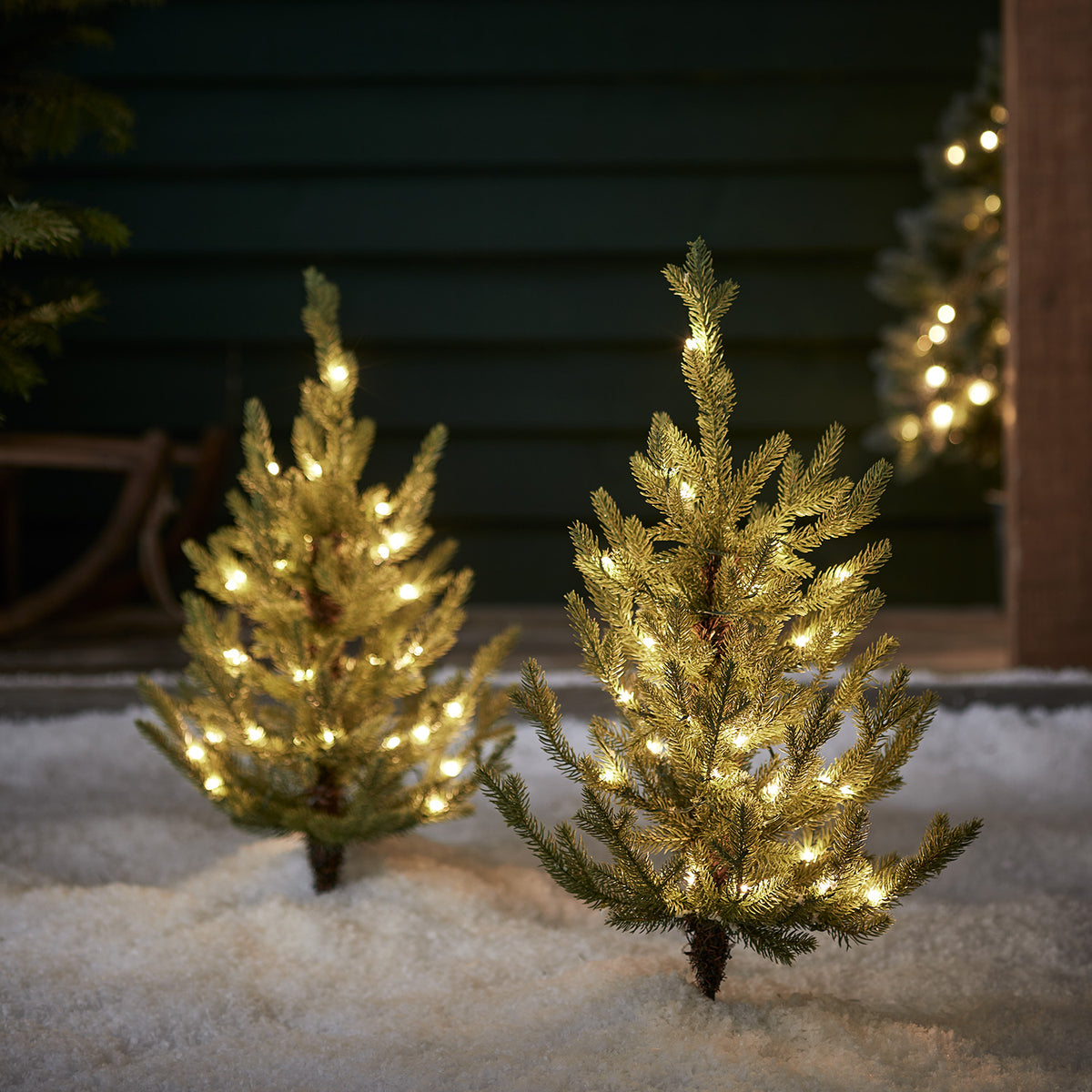 Zwei 60cm hohe LED Nordmanntannen mit warmweißen Lichtern im Schnee bei Nacht