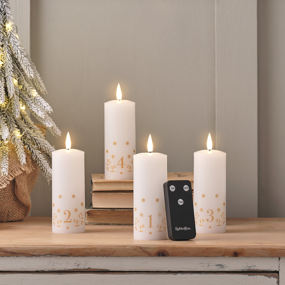 Vier elfenbeinfarbene TruGlow LED-Adventskerzen mit goldenen Zahlen und Fernbedienung auf Holztisch