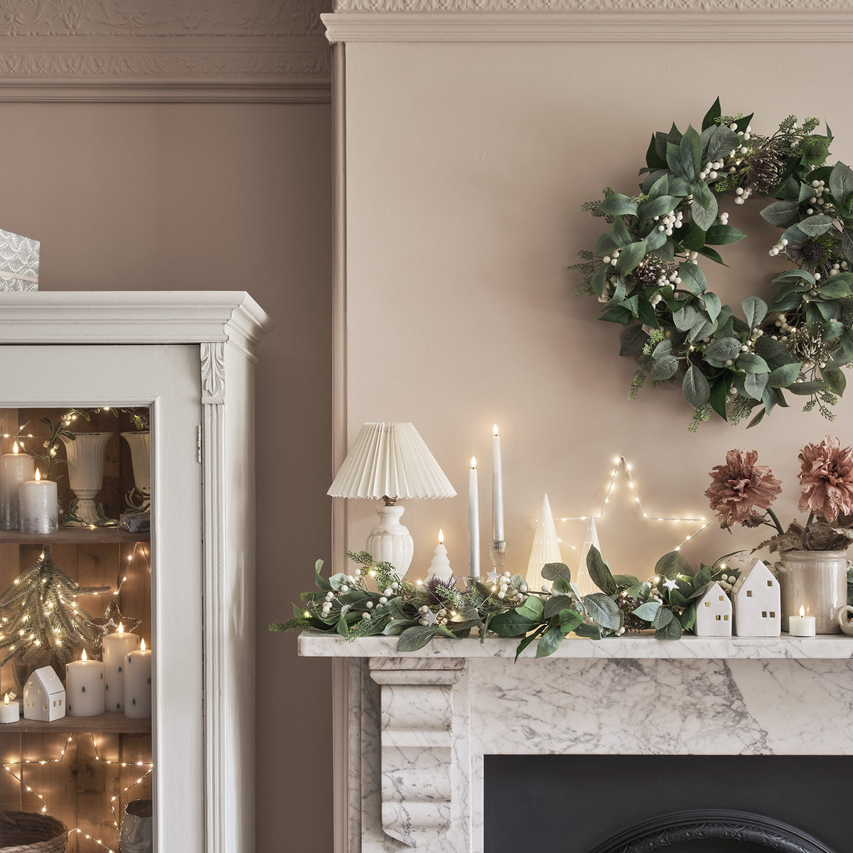 Weihnachtskranz an Wand über Kamin mit Girlande, Kerzen und Dekorationen im Raum