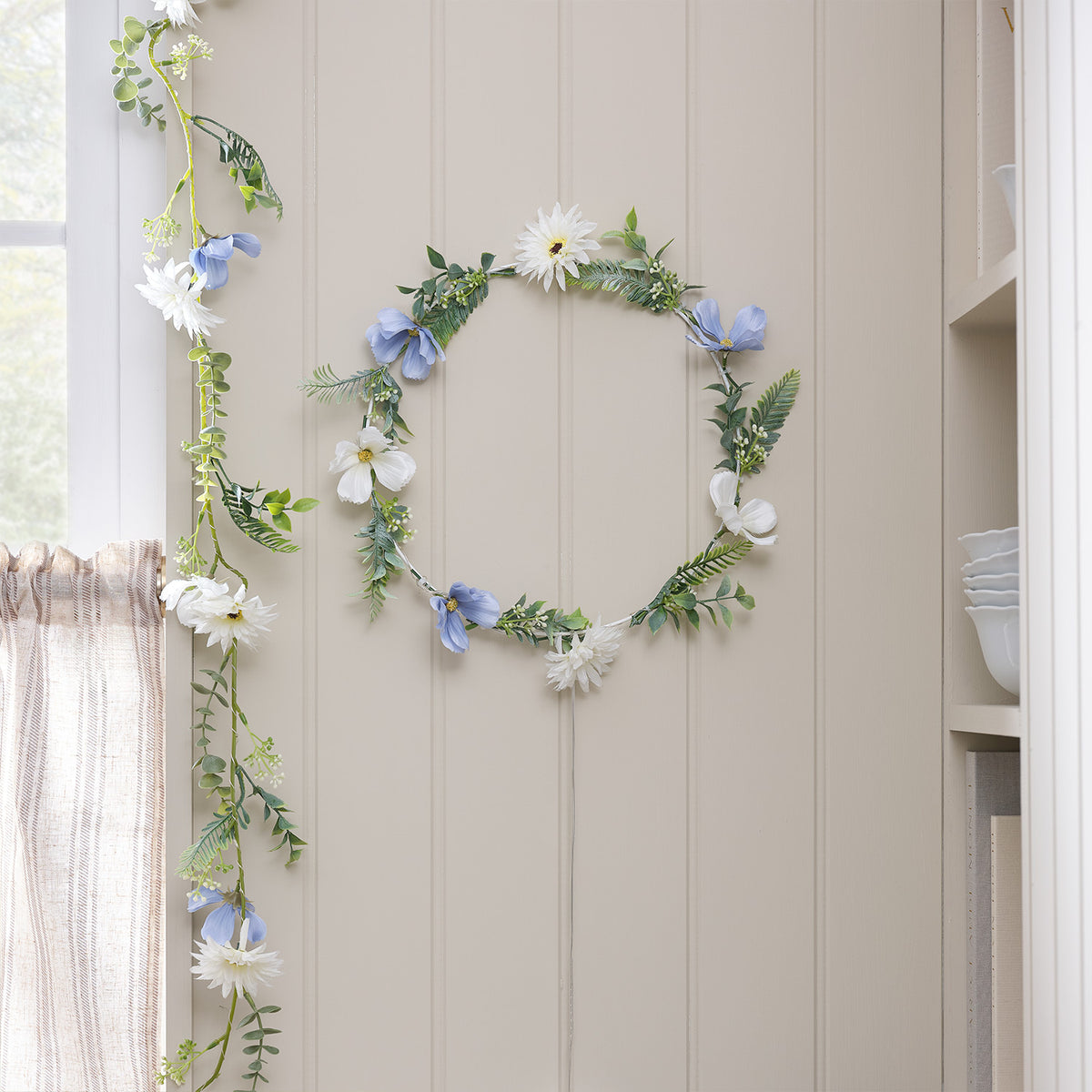Beleuchteter Kranz und Girlande mit blauen und weißen Blüten indoor