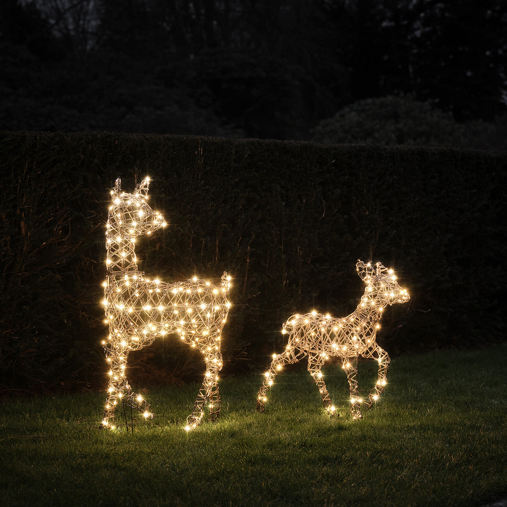 LED-Rentier Hirschkuh und Rehkitz in warmweiß leuchtend im Garten vor Hecke bei Nacht