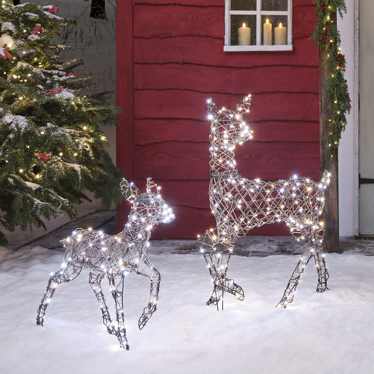 LED-Rentier Hirschkuh mit warmweißen und Rehkitz mit kaltweißen LEDs leuchtend im Schnee