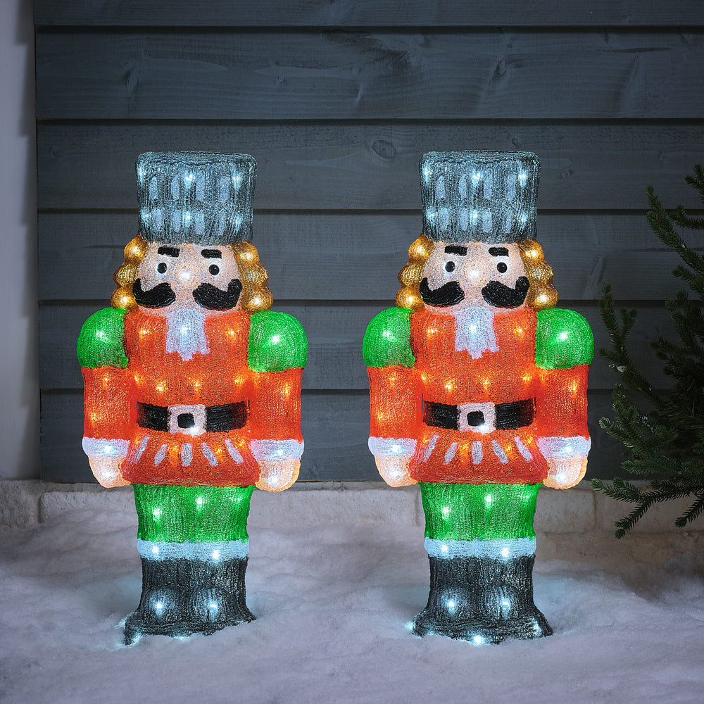 Zwei beleuchtete LED-Nussknacker aus Acryl mit bunter Uniform und Timerfunktion im Schnee