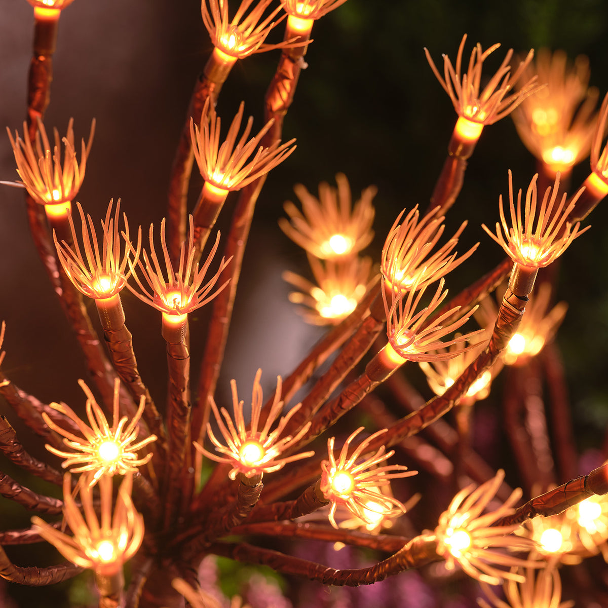 Nahaufnahme der warmweißen LED-Lichter in den goldfarbenen Pusteblumen-Gartensteckern