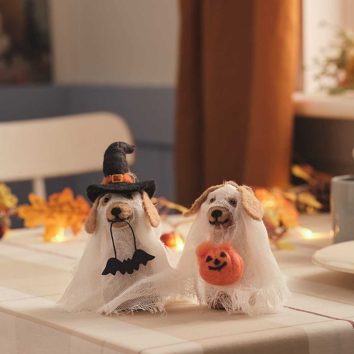 Zwei Halloween-Hunde aus Filz mit Geisterumhang, einer mit Hexenhut und Fledermaus, der andere mit Kürbis