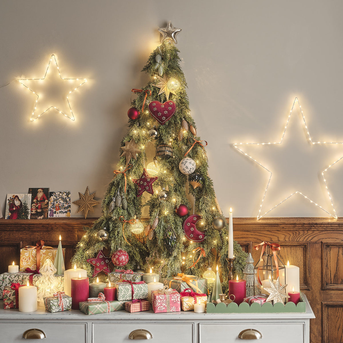 Weihnachtsgirlande mit warmweißen LEDs auf Holzkommode vor Wand mit Bildern