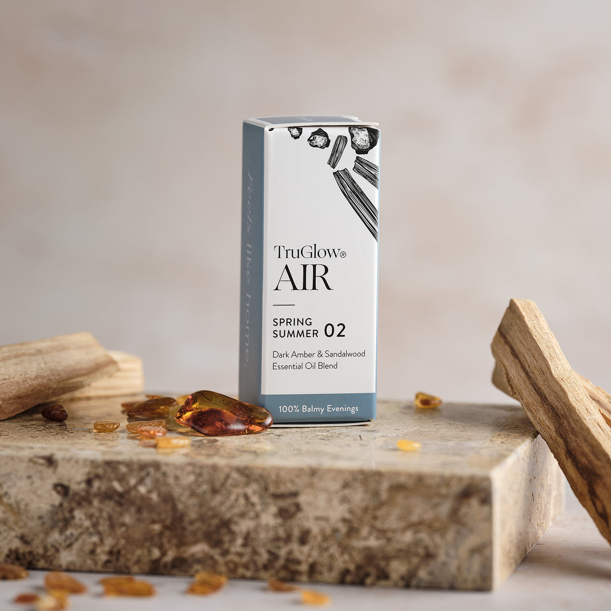Verpackung des TruGlow AIR ätherischen Öls Dunkler Amber & Sandelholz mit Bernstein und Sandelholzstücken