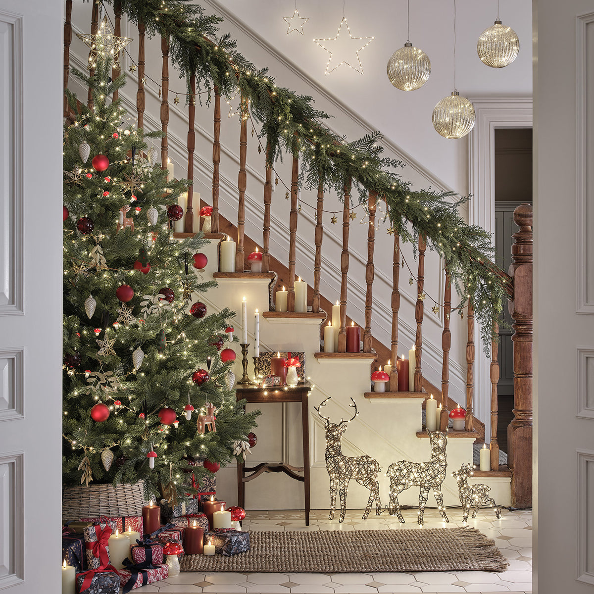 Weihnachtlich dekorierter Innenraum mit Tanne, Geschenken und beleuchteten LED-Rentieren an der Treppe