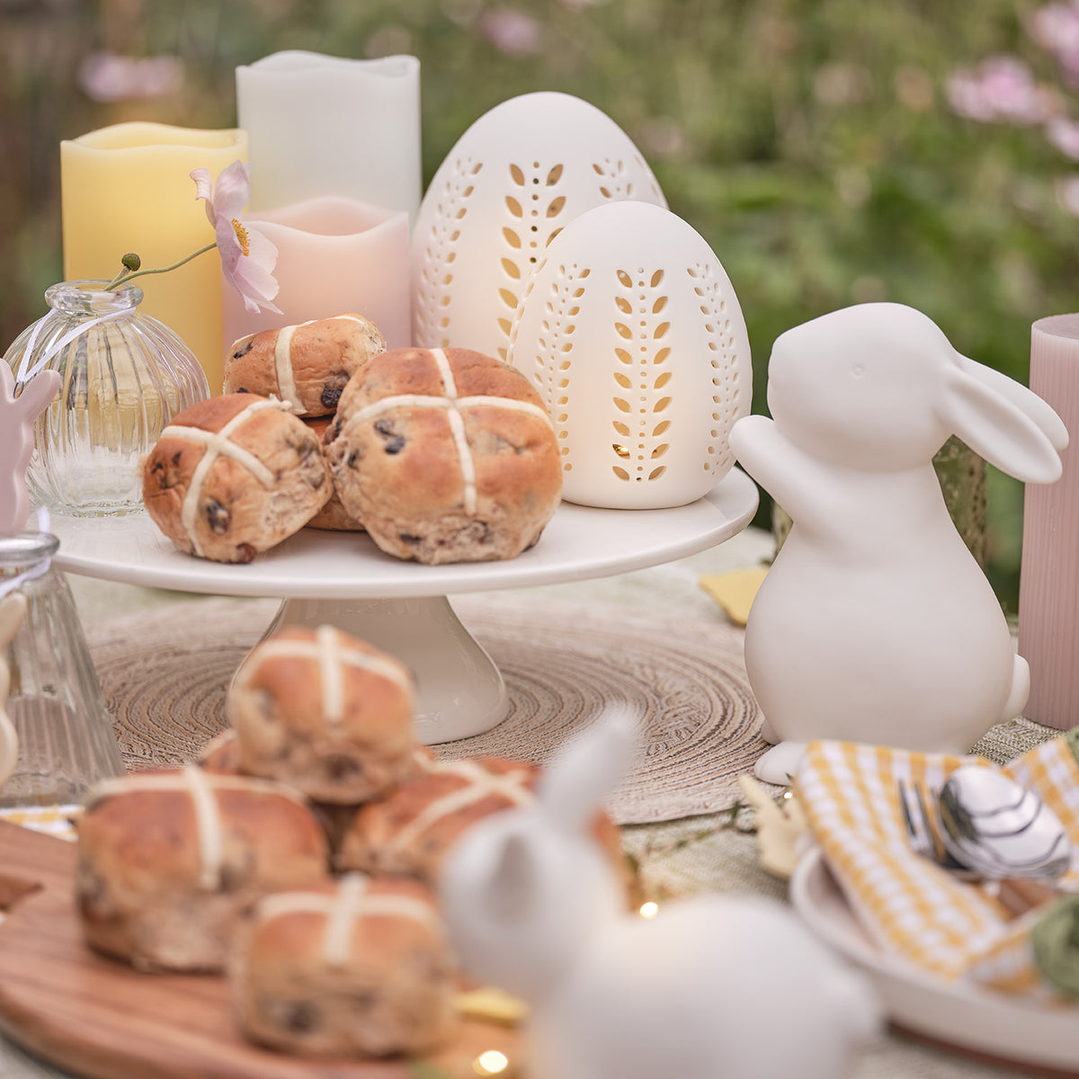 Beleuchteter Porzellan-Osterhase neben Osterkerzen und Deko auf Holzkommode