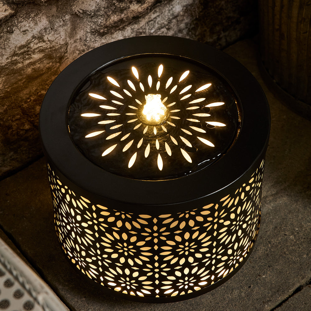 Nahaufnahme des Lucia Gartenbrunnens mit warmweißer LED-Beleuchtung und Wasserfontäne