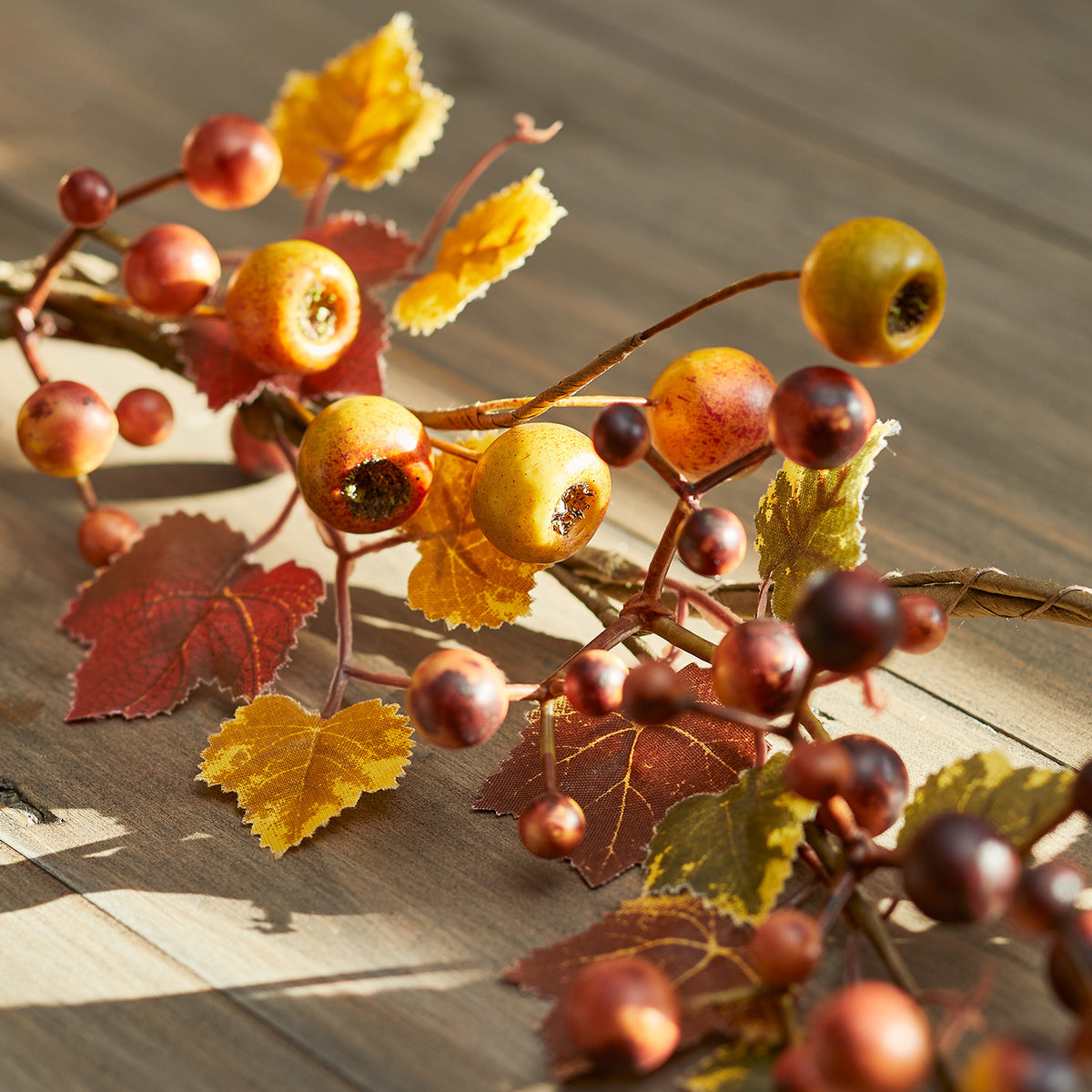 Nahaufnahme der herbstlichen Beeren und bunten Blätter der Girlande auf Holztisch