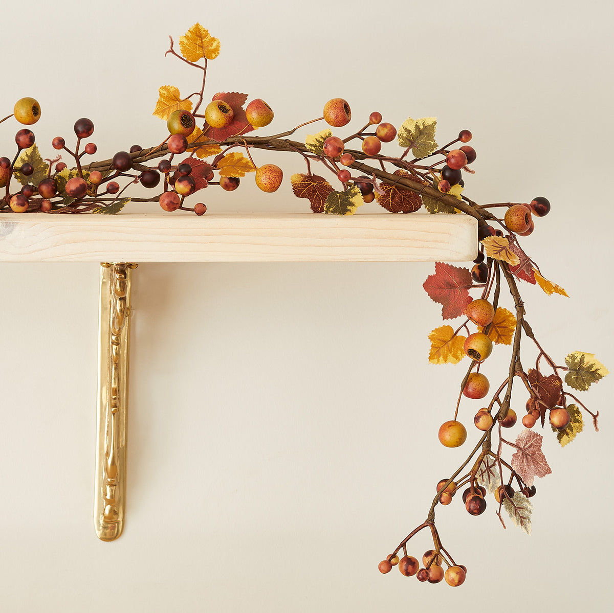Herbstgirlande mit Beeren und bunten Blättern ohne Beleuchtung auf einem Holzregal