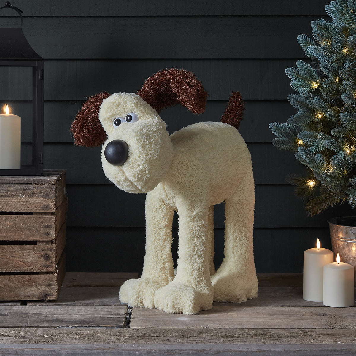 Beleuchtete Gromit LED Figur mit flauschigem Fell auf Holzboden neben Kerzen und Tannenzweig