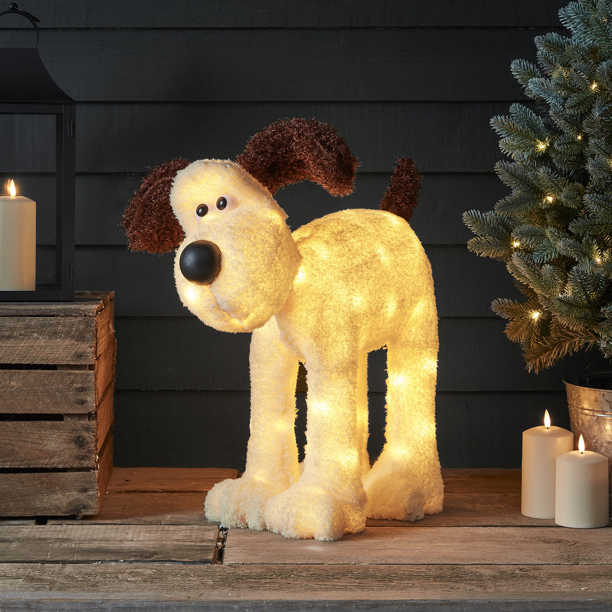 Unbeleuchtete Gromit LED-Figur mit rot-weißem Schal vor Weihnachtsbaum und Geschenken