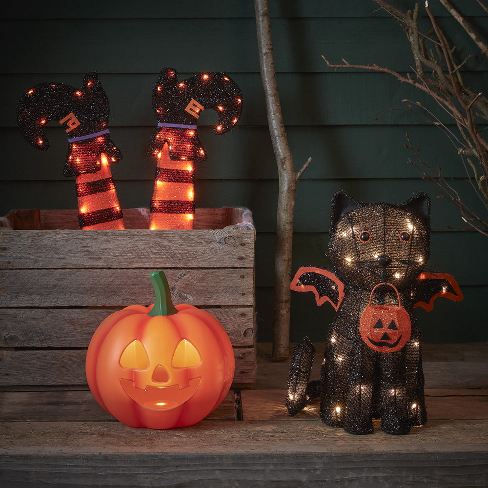 Halloween-Dekoset mit leuchtendem Kürbis, Hexenbeinen und schwarzer Katze mit Fledermausflügeln