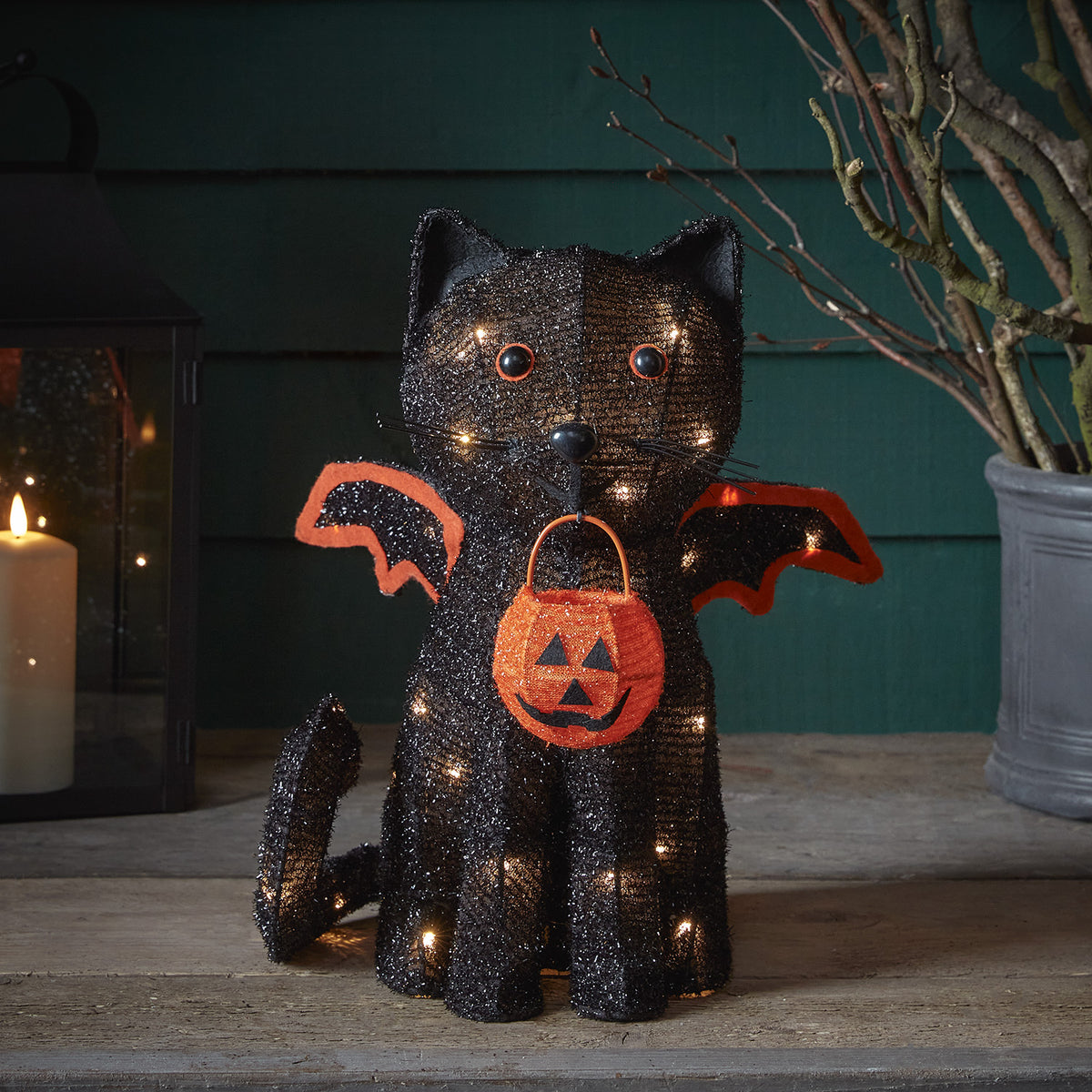 Schwarze Halloween-Katze mit Fledermausflügeln und Jack-O-Lantern-Körbchen