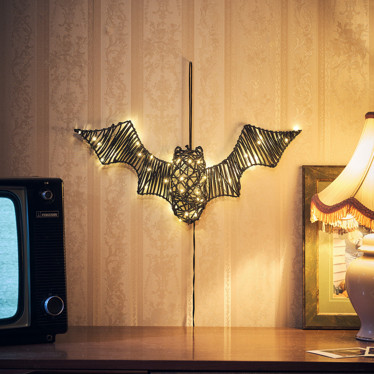 LED Fledermaus aus Rattan auf einem Tisch neben Retro-Fernseher und Lampe