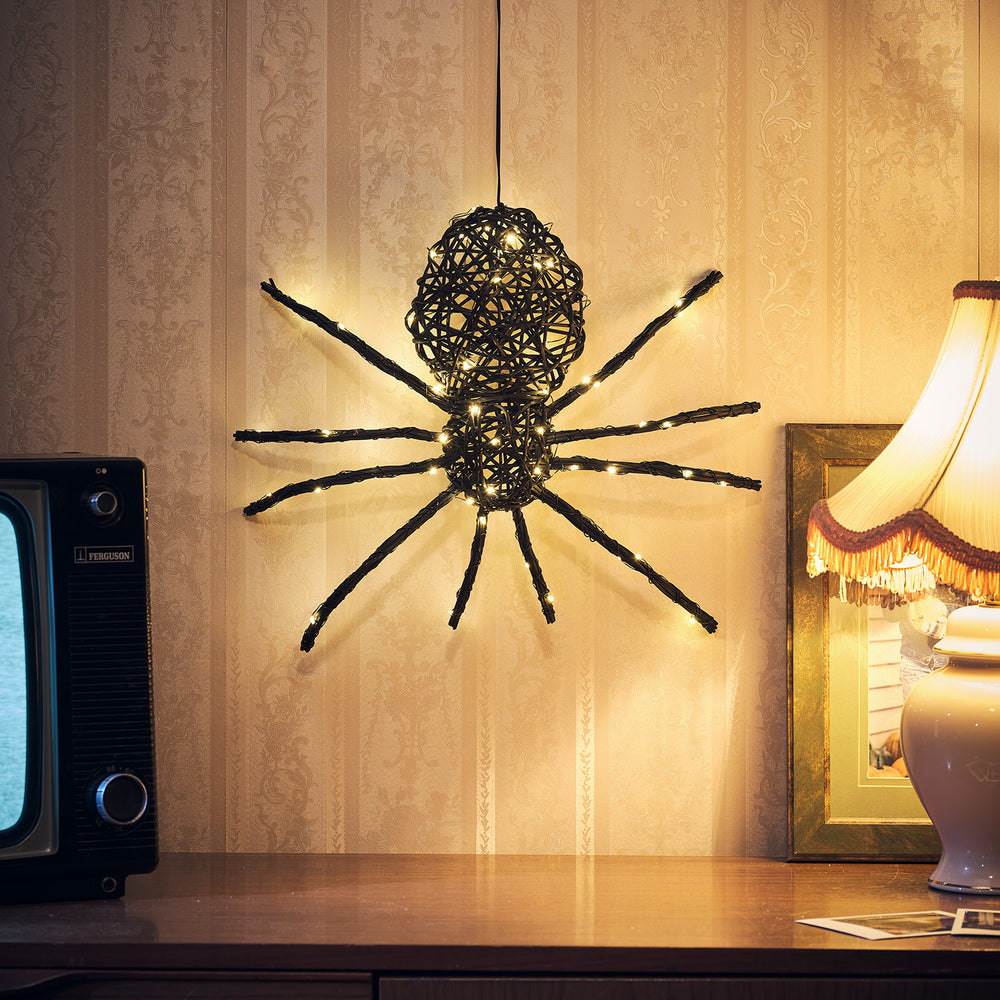 LED Rattan Spinne mit warmweißen Lichtern an Wand über Kommode mit Lampe und Fernseher